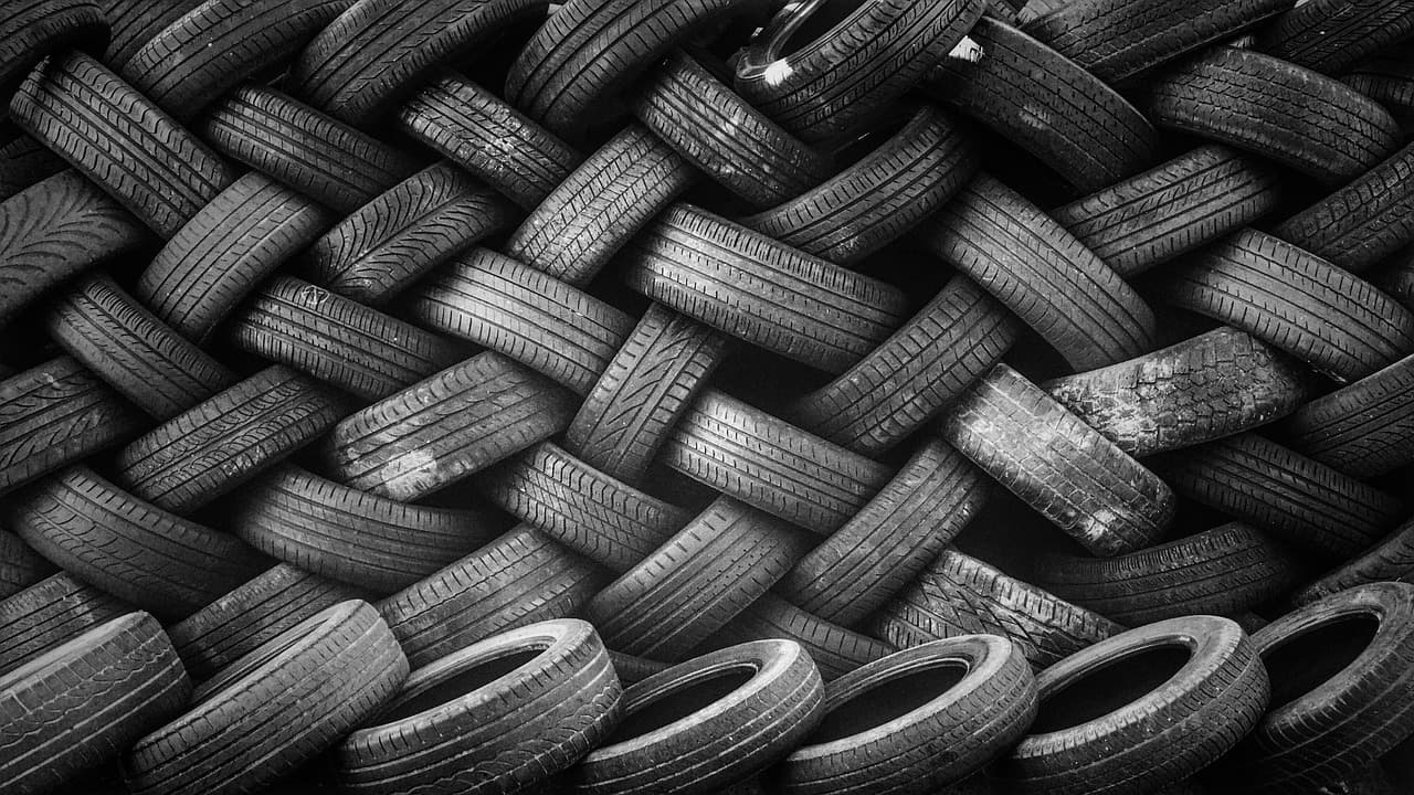 Used car tyres stacked in rows, in black and white
